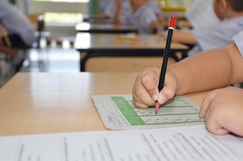 Um aluno da escola primária escreve com um lápis em um teste enquanto está na escola.