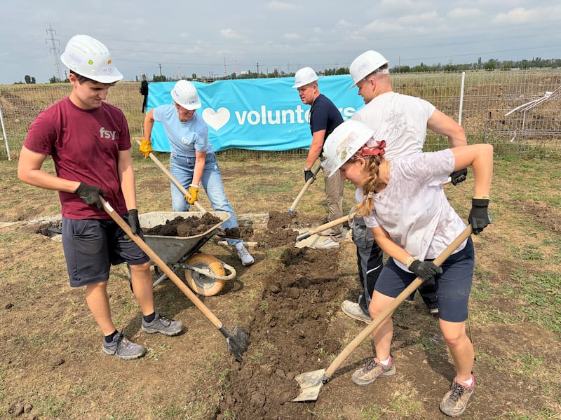 Voluntários de A Igreja de Jesus Cristo dos Santos dos Últimos Dias trabalham juntamente com um profissional de construção da Habitat for Humanity Romania para preparar estruturas de paredes de madeira para casas em construção em Berceni, Romênia, em agosto de 2026.