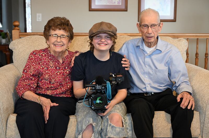 Paige Olsen — vencedora da categoria de ilustração de projeto no All-American High School Film Festival, ao centro — sorri para uma foto com seus avós Linda Mortensen e Ron Mortensen enquanto filma um documentário sobre a vida de Ron em Perry, Utah, fevereiro de 2025.