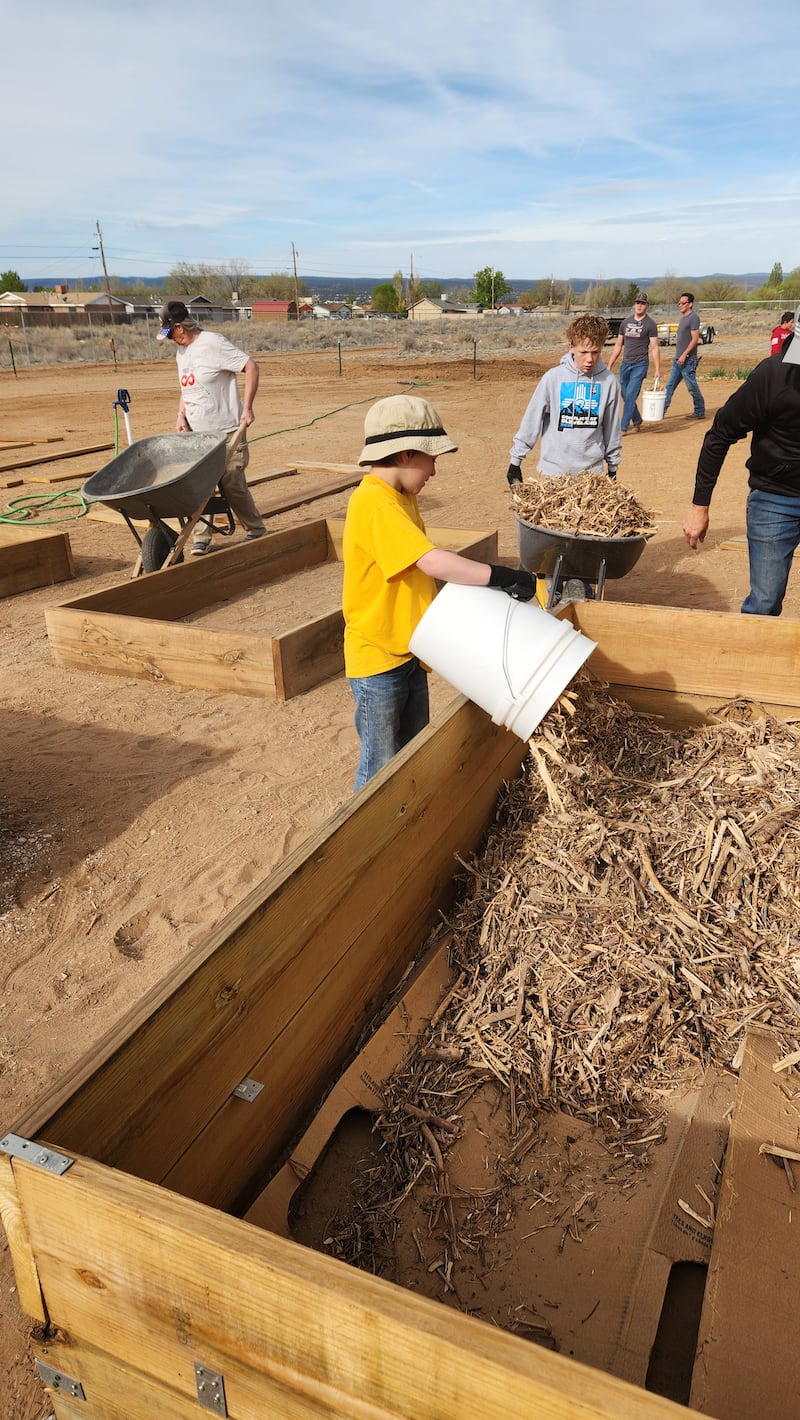 Jovens e adultos preparam novas caixas de jardim na Despensa Comunitária e Jardim da Esperança em Grants, Novo México, em 11 de abril de 2026.