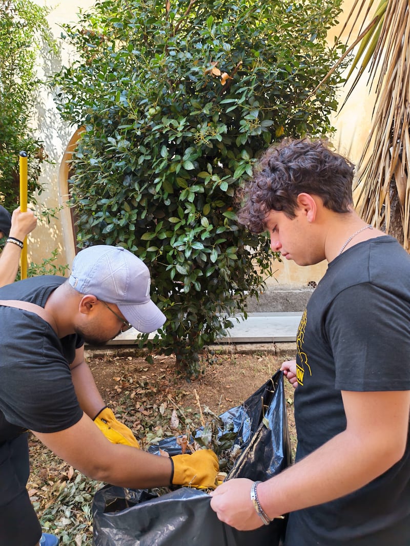 Voluntários da Ala de Palermo, Itália, recolhem folhas e detritos do pátio enquanto limpam o terreno de Casa Scalabrini 634 em Roma, Itália.