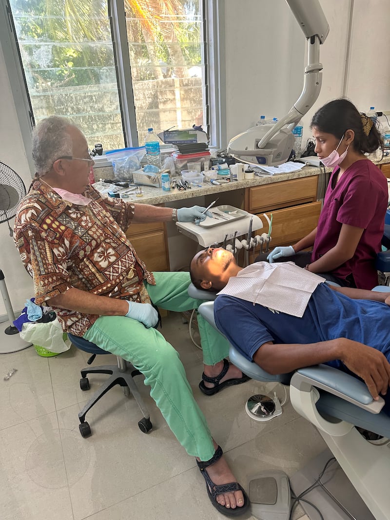 Wayne Chisholm trabalha nos dentes de um paciente na clínica dentária de Moroni em Eita, Kiribati, julho de 2024.