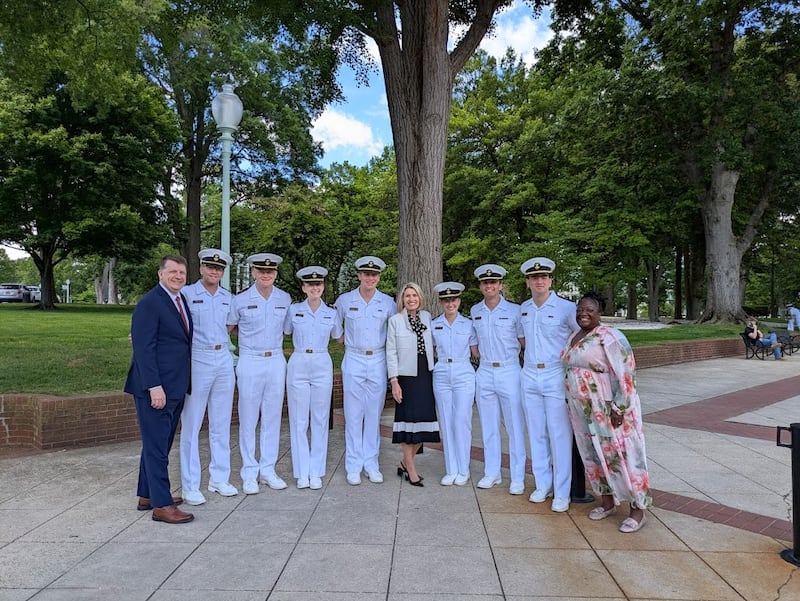 A Presidente Camille N. Johnson, o Elder Michael P. Brady e a irmã Eme Martin tiram uma foto com sete Santos dos Últimos Dias que são aspirantes atuais na Academia Naval dos Estados Unidos em Annapolis, Maryland, na sexta-feira, 15 de maio de 2026.
