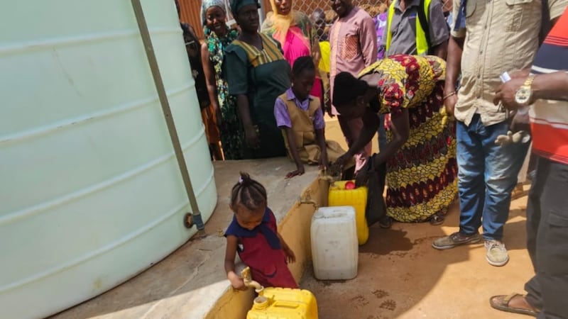 Residentes da comunidade enchem recipientes com água limpa após uma cerimônia de entrega de posse em Freetown Ocidental, Serra Leoa, em 3 de abril de 2026.