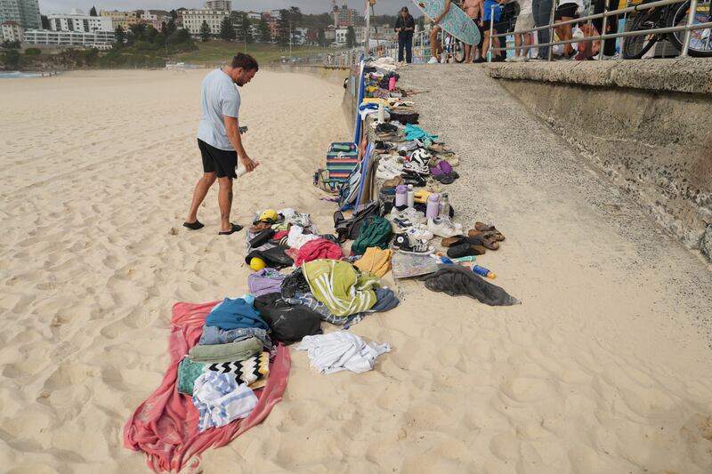 Um homem olha para os pertences empilhados após um tiroteio em Bondi Beach, Sydney, Austrália.