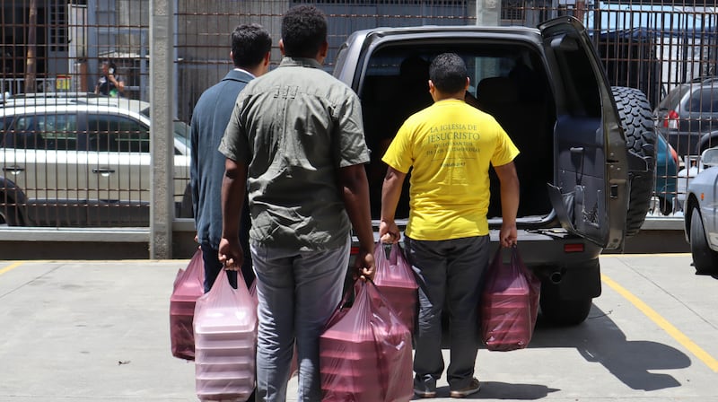 Voluntários de A Igreja de Jesus Cristo dos Santos dos Últimos Dias carregam refeições preparadas para serem entregues aos necessitados em 1º de julho de 2026, em La Guaira, Venezuela.