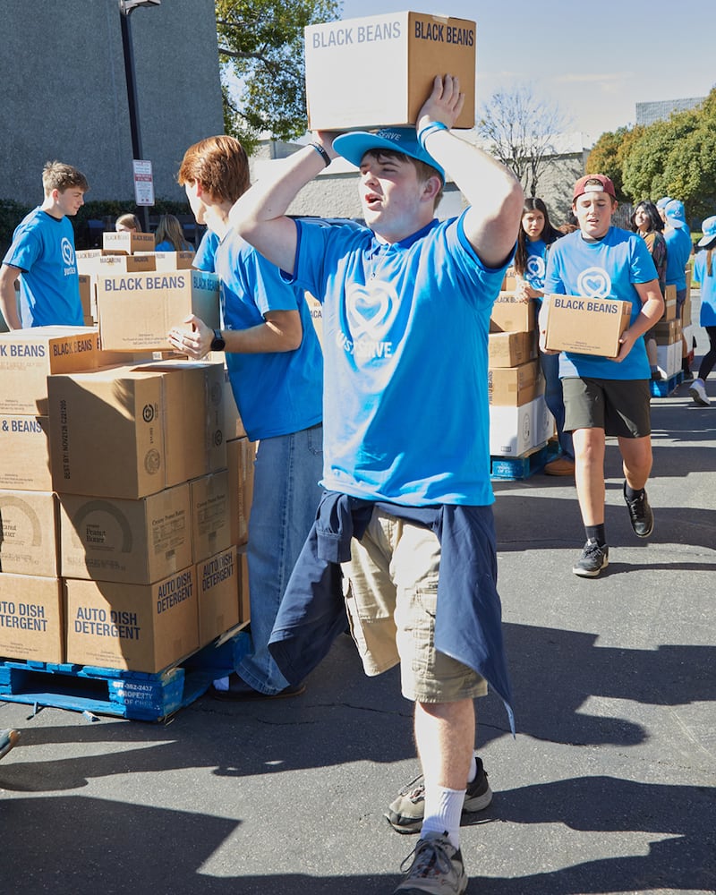 Joseph Gleason, um voluntário jovem do JustServe, ajuda a mover caixas de uma doação de alimentos America250 da Igreja de Jesus Cristo dos Santos dos Últimos Dias para paletes a fim de serem entregues a quase uma dúzia de diferentes instituições de caridade na área de Irvine, Califórnia, no sábado, 21 de fevereiro de 2026.