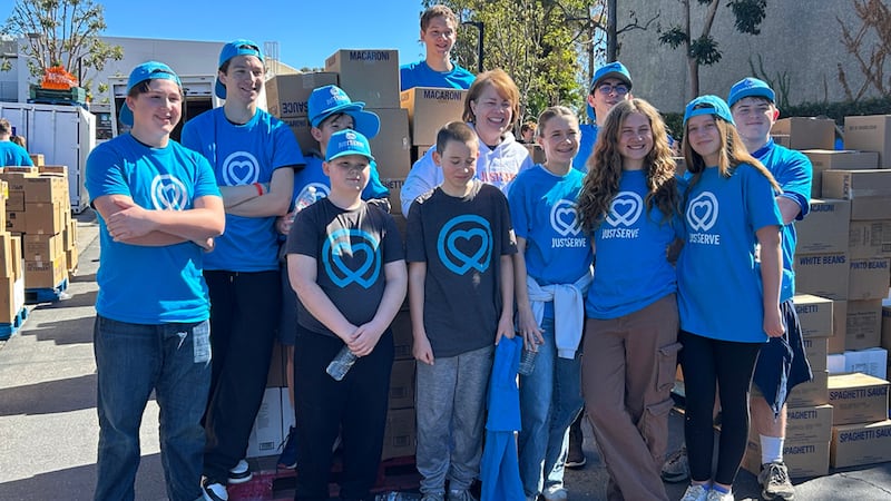 Sharon Eubank, diretora de Serviços Humanitários da Igreja, ao centro, posa com jovens voluntários do JustServe no sábado, 21 de fevereiro de 2026, no South County Outreach em Irvine, Califórnia, após uma doação de alimentos do America 250 da Igreja.