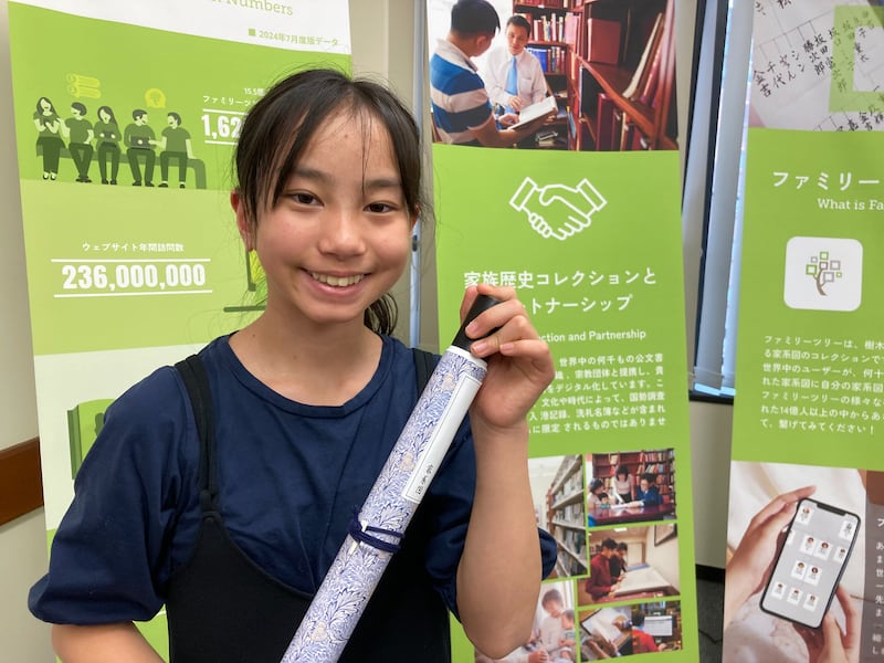 Uma jovem exibe um pergaminho genealógico que ela fez durante uma feira de história da família de Kagoshima, Japão, 23 de fevereiro de 2026.
