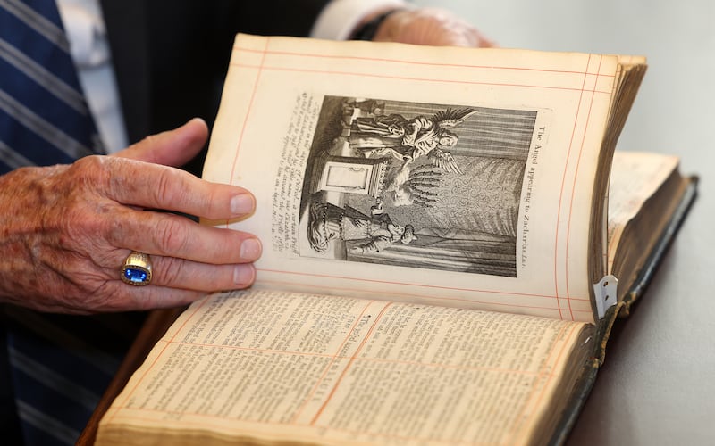 Élder Jeffrey R. Holland verifica uma Bíblia da Restauração de Carlos II de seu reinado após a Guerra Civil Inglesa. O Rev. Andrew Teal presenteou a Igreja na quarta-feira, 5 de outubro de 2022 , no escritório de Élder Holland no Edifício de Administração da Igreja em Salt Lake City.