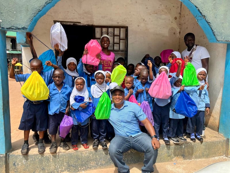 Konrad Barjuah, ao centro, entrega kits escolares a uma escola na Libéria.