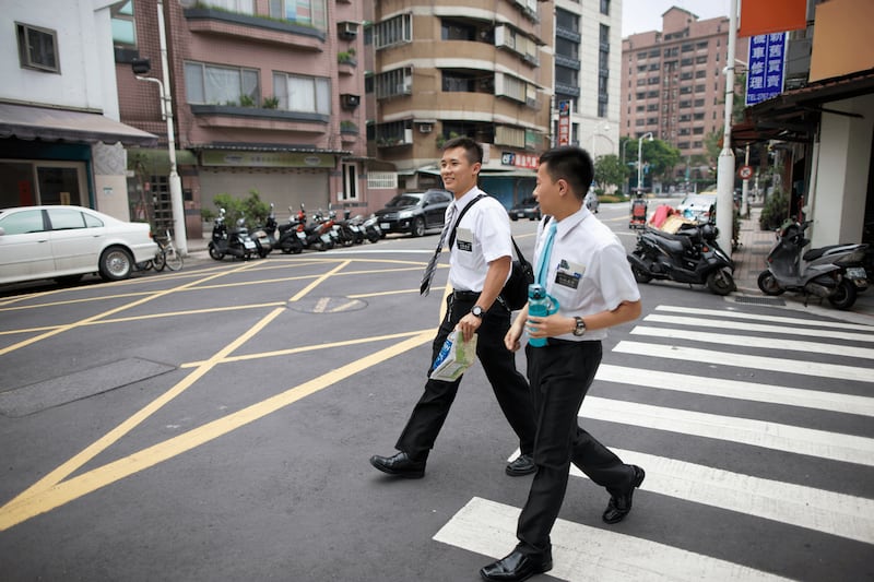 Um par de missionários em tempo integral atravessa a rua em Taiwan em 2025.