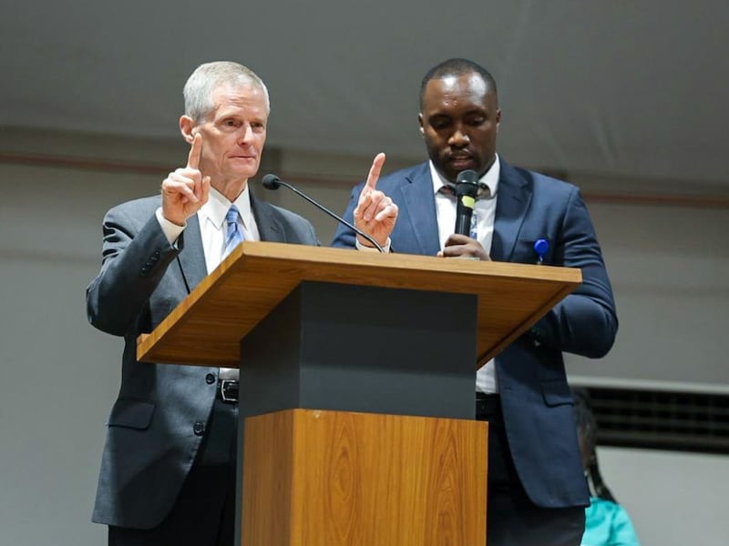 Elder David A. Bednar fala no púlpito ao lado de um tradutor durante o devocional de Kigali, Ruanda, 17 de março de 2026.