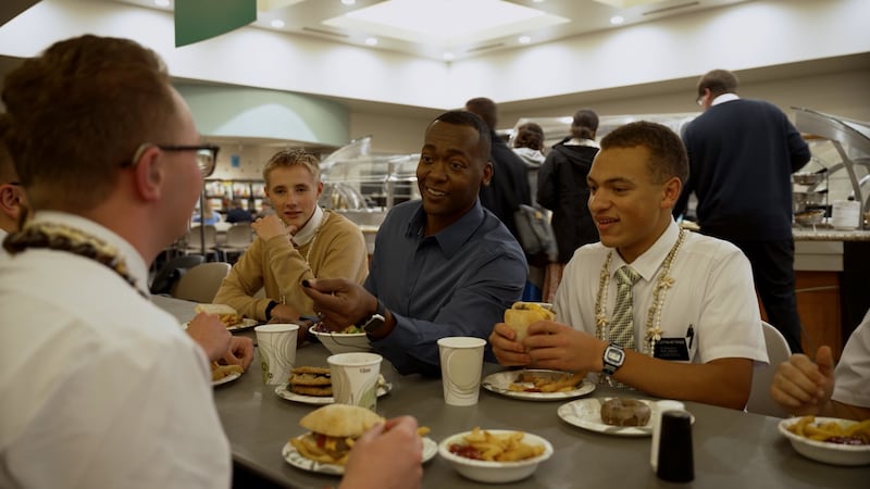 Missionários conversam com o apresentador de vídeos Danor Gerald enquanto comem na cafeteria no Centro de Treinamento Missionário de Provo.