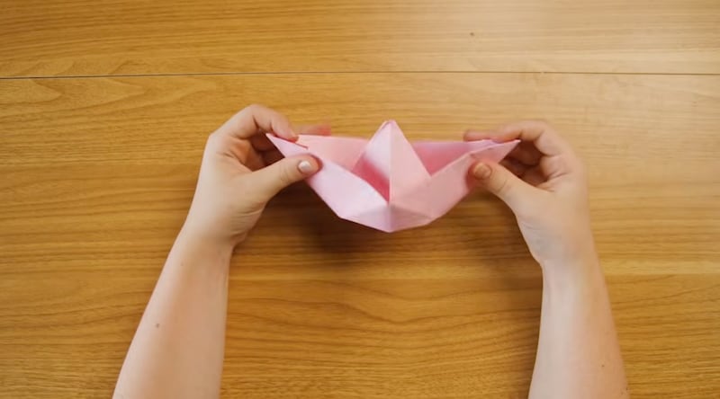 Uma criança dobra um papel em forma de barco como a Arca de Noé.