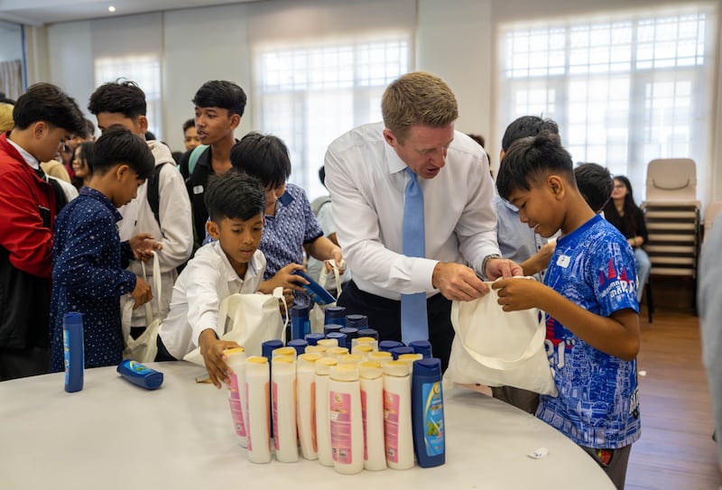 O presidente geral dos Rapazes, Timothy L. Farnes, auxilia um jovem durante um projeto de serviço para montar mais de 200 bolsas de cuidados para um orfanato em Phnom Penh, Camboja, em maio de 2026.