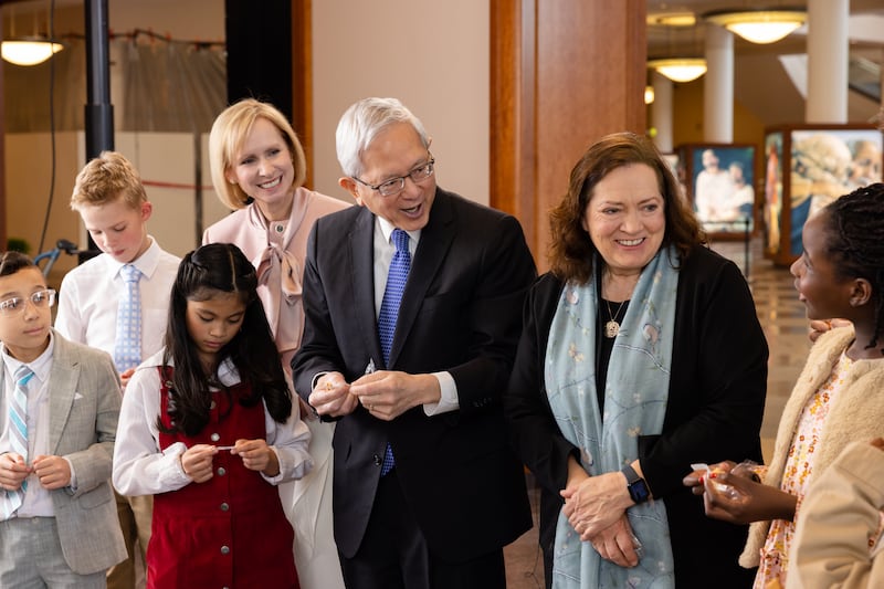 Elder Gerrit W. Gong, irmã Susan Gong e irmã Amy A. Wright abrem biscoitos da sorte com crianças durante a filmagem do Amigo para Amigo de maio de 2026.