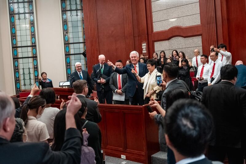 Élder Dieter F. Uchtdorf e Irmã Harriet Uchtdorf se despedem com um mini-sinal de coração com as mãos dos membros de Hong Kong.