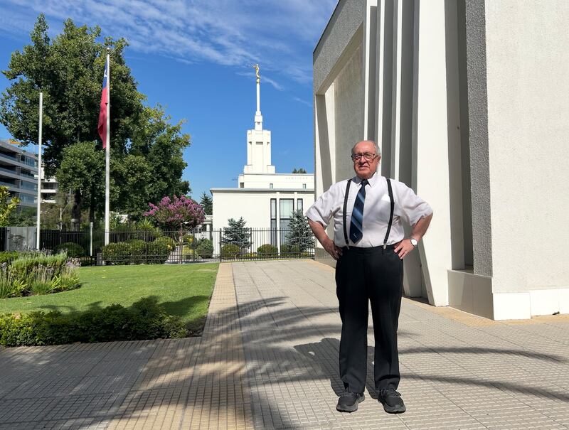Polibio González está do lado de fora de uma capela dos Santos dos Últimos Dias com o Templo de Santiago Chile ao fundo. González supervisionou a construção de mais de 90 capelas no Chile.