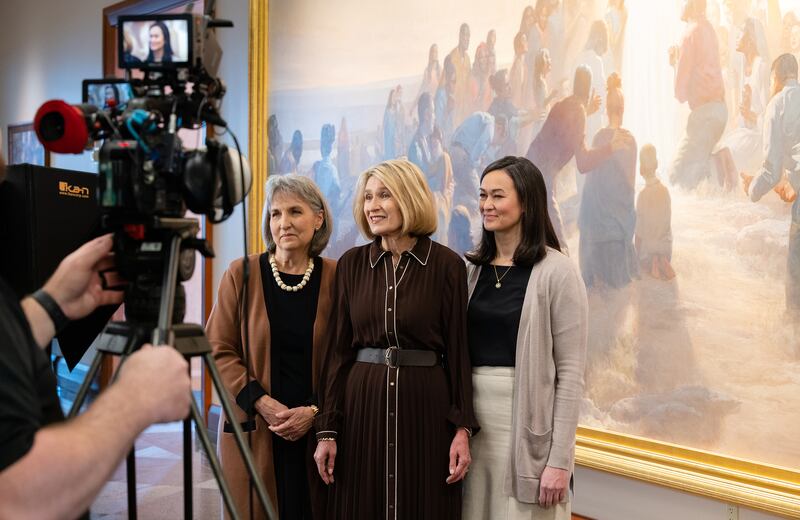 A presidência geral da Sociedade de Socorro grava uma parte do devocional mundial da Sociedade de Socorro de 2026 em frente a uma grande pintura no Centro de Conferências em Salt Lake City.