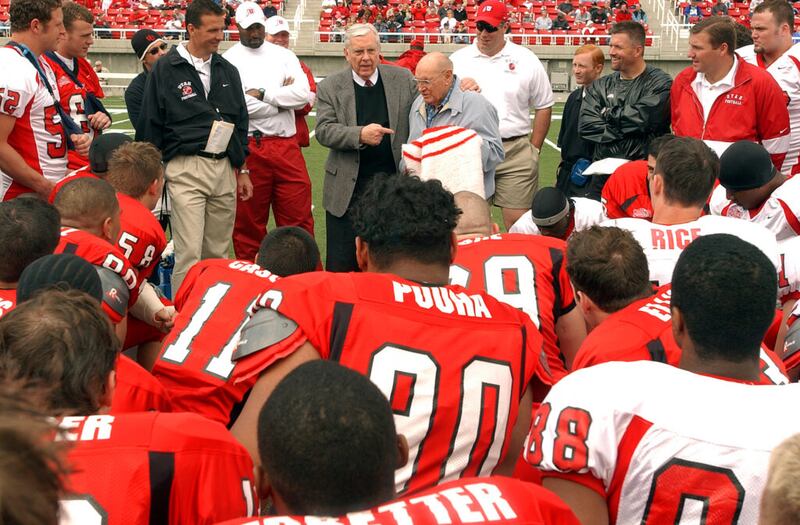 O então Élder M. Russell, Ballard e Élder Joseph B. Wirthlin conversam com o time de futebol americano da Universidade de Utah antes de um jogo dos Utes, em 19 de abril de 2003. Élder Wirthlin foi presenteado com uma camisa do time. Crédito: Jeffrey D. Allred, Deseret News