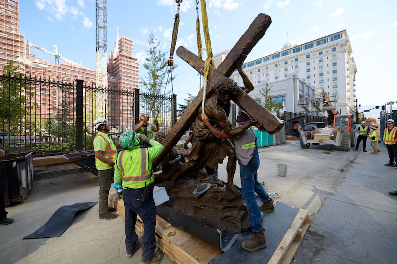 Membros da equipe instalam a estátua "Jesus Christ Carrying the Cross", criada por Michael Hall, ao sul do Templo de Salt Lake na quarta-feira, 17 de setembro de 2025.