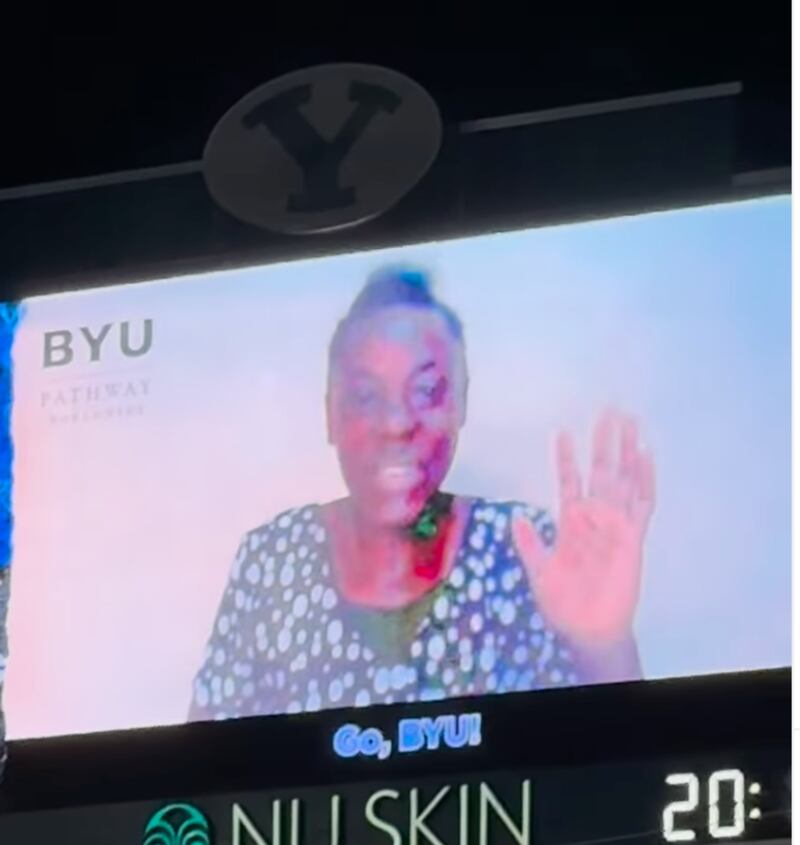 Faith Kisayke, uma estudante da BYU-Pathway de Uganda, acena após dizer a oração de abertura antes de um jogo de futebol americano da BYU.