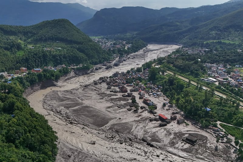 Casas danificadas ficam precariamente perto das margens inchadas e entulhadas do Rio Trishuli após enchentes repentinas no distrito de Nuwakot do Nepal, quarta-feira, 26 de agosto de 2026.