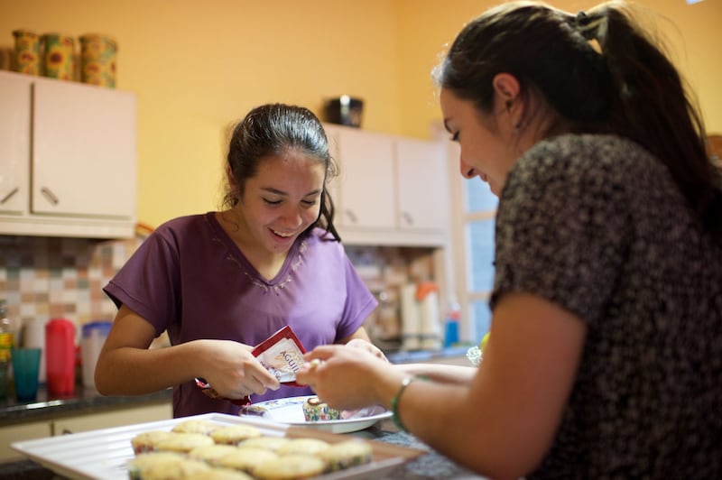 Moças no Paraguai fazem cupcakes. Fazer uma sobremesa favorita da família é uma das muitas maneiras de celebrar o Mês da História da Família em outubro.