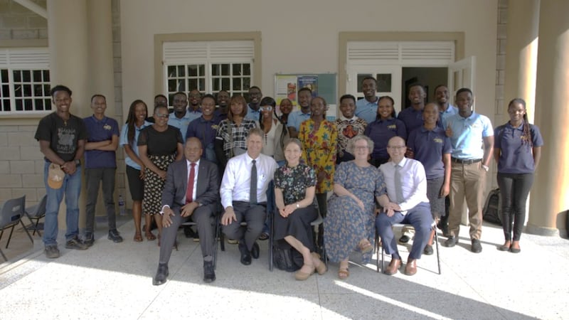 Elder Frederick Kamya, Elder Carl B. Cook, Sister Lynette Cook, Sister Isabelle Giraud-Carrier e Elder Christophe Giraud-Carrier tiram uma foto com líderes dos JAS da Estaca Kampala Uganda Norte em 17 de março de 2026.