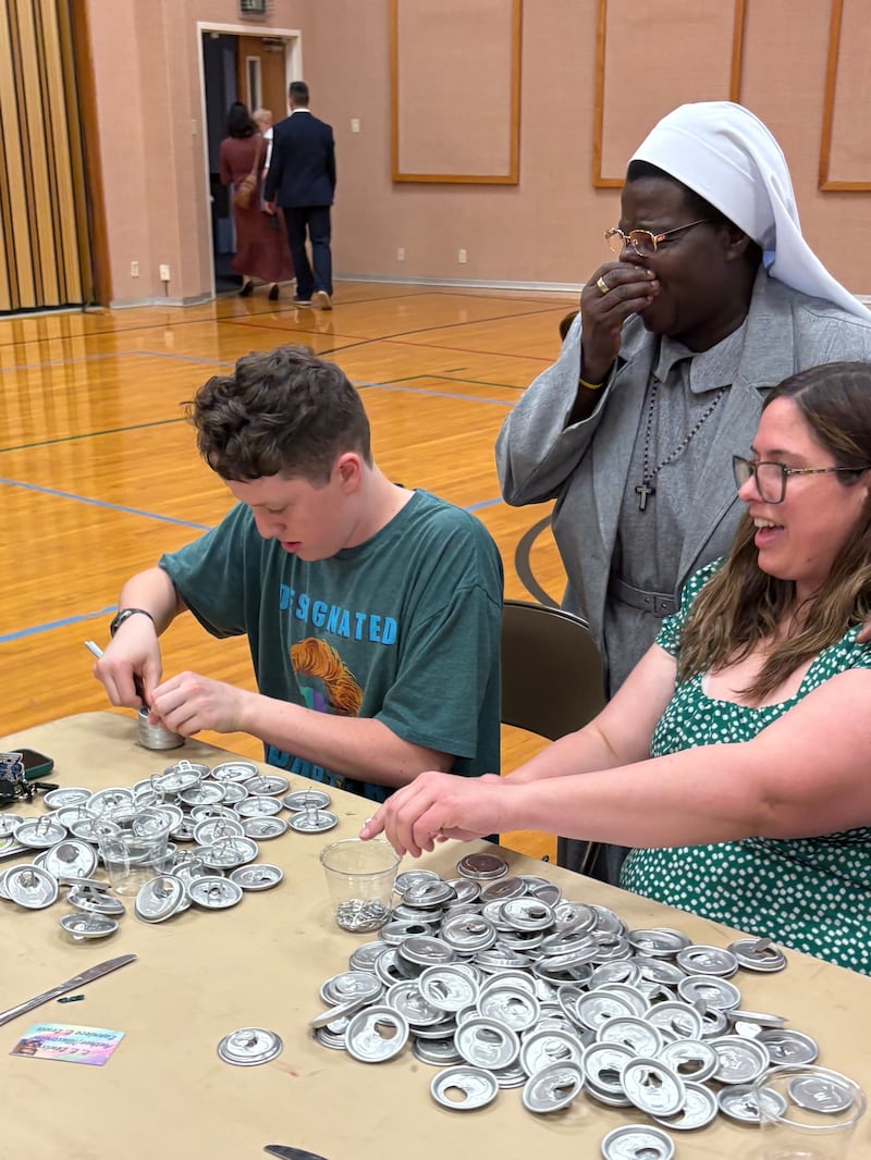 A Sister Rosemary Nyirumbe supervisiona membros da Estaca Norman Oklahoma enquanto eles participam de um projeto de serviço para retirar lacres de tampas de latas na cidade de Oklahoma, Oklahoma, em 8 de março de 2026.