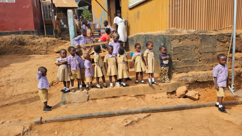 Crianças em idade escolar observam durante uma doação de um poço tubular de água em New England Ville, no oeste de Freetown, Serra Leoa, em 3 de abril de 2026.