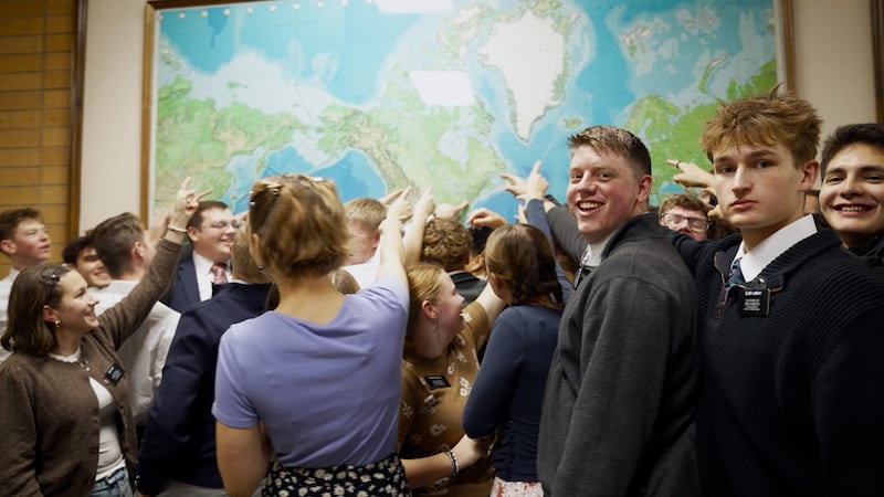 Missionários apontam para sua missão designada em um mapa mundial durante a filmagem de um novo vídeo no Centro de Treinamento Missionário de Provo.