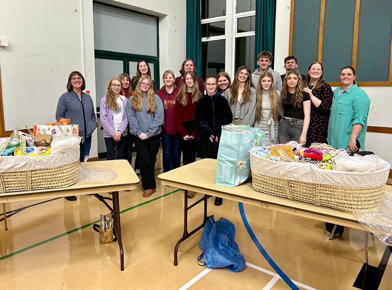 Jovens da Estaca Inglaterra Northampton tiram uma foto com algumas das cestas que eles montaram com suprimentos para bebês para dar a novas mães durante uma atividade de serviço em outubro de 2024.