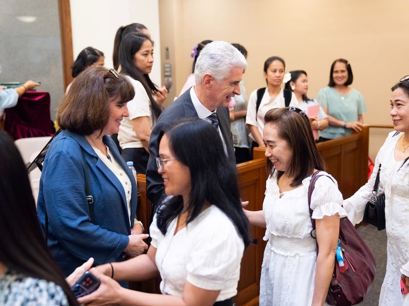 Elder Gérald Caussé do Quórum dos Doze Apóstolos e Sister Valérie Caussé cumprimentam membros trabalhando longe de casa de um ramo de Hong Kong em 26 de abril de 2026.