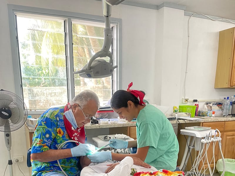 Wayne Chisholm trabalha nos dentes de um paciente na clínica Moroni em Eita, Kiribati, 2024.