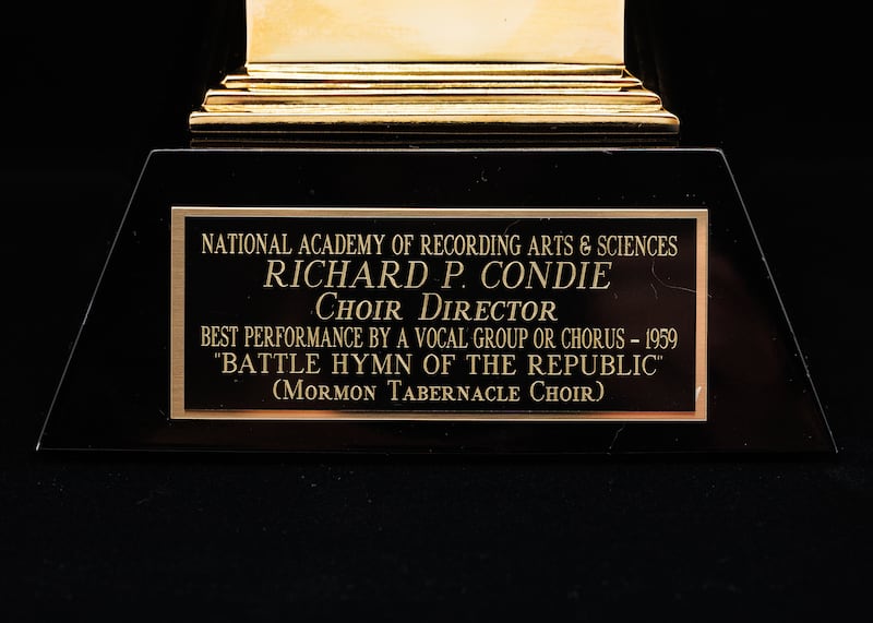 O Grammy Award, que se parece com um gramofone antigo, indica que foi apresentado a Richard P. Condie pela gravação de "Battle Hymn of the Republic" do Coro do Tabernáculo na Praça do Templo.