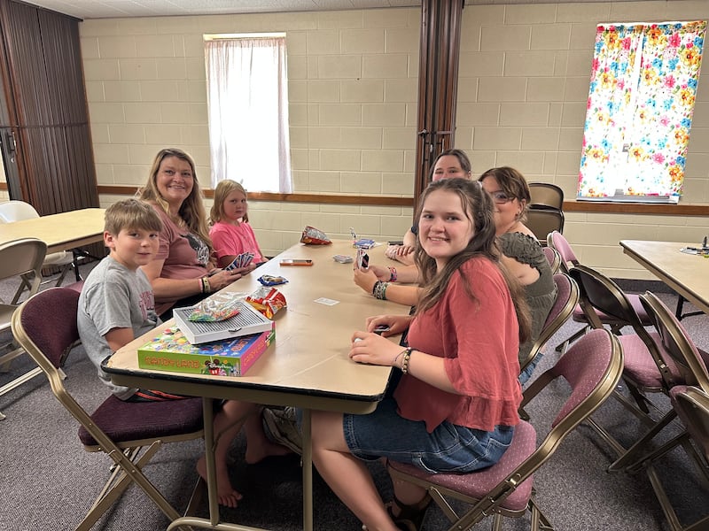 A Presidente das Moças da Estaca de Pueblo Colorado, Irmã Misty Koller, joga um jogo com sua família no Centro de Estaca de Pueblo Colorado em 10 de julho de 2026. A família Koller ofereceu uma sala de jogos para os jovens dos evacuados do incêndio florestal de Aspen Acres durante uma atividade de estaca.