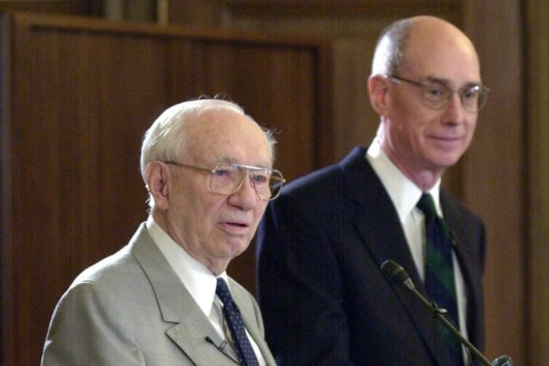 O Presidente Gordon B. Hinckley e Elder Henry B. Eyring anunciam planos para mudar o Ricks College para BYU–Idaho, uma universidade de quatro anos.