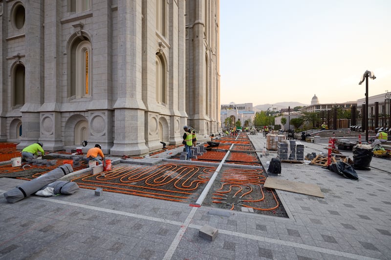 Equipes instalam pavimentação de pedra sobre os tubos de degelo fora do Templo de Salt Lake na cidade de Salt Lake na terça-feira, 23 de junho de 2026.