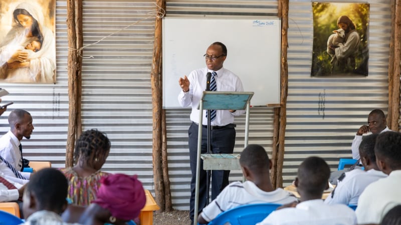 Elder Johnny O. Baddoo aborda os membros do Ramo Kakuma no Acampamento de Refugiados de Kakuma no Quênia em 19 de junho de 2026.