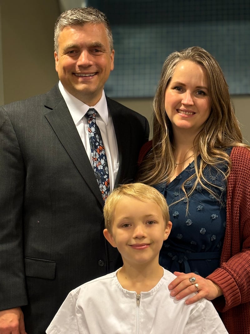 Traci Law — compositora de "Little Baby in a Manger" — e seu marido, Ryan, sorriem com o filho Joshua no dia de seu batismo de Spanish Fork, Utah, novembro de 2024.