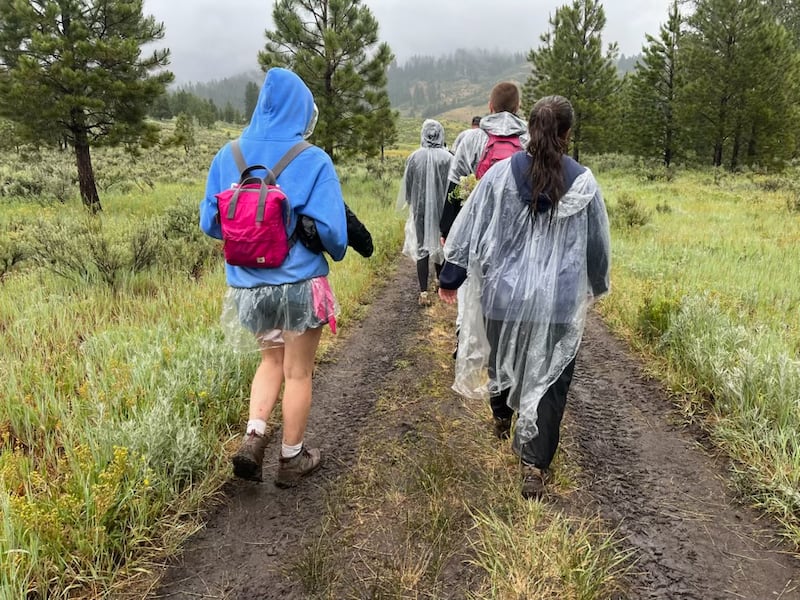 Jovens da Estaca Spokane Valley Washington caminham na chuva durante o Trek em Bend, Idaho em 26 de junho de 2026.