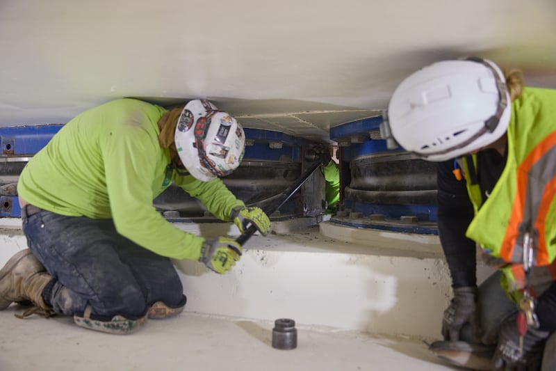 Equipes removem parafusos de uma das placas de um isolador de base localizado a 20 pés abaixo do Templo de Salt Lake em Salt Lake City na quinta-feira, 25 de junho de 2026.