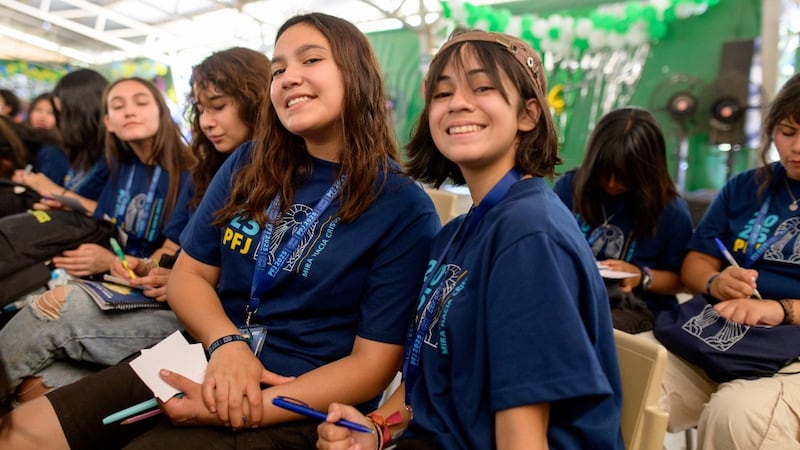 Jovens mulheres fazem uma pausa para uma foto durante um projeto de serviço embalando materiais escolares durante uma sessão de FSY do Chile em janeiro de 2025.