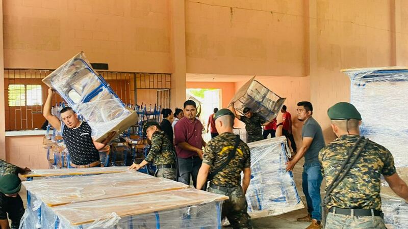 Voluntários descarregam material escolar e móveis em Melchor de Mencos, Petén, Guatemala, em 25 de novembro de 2022.