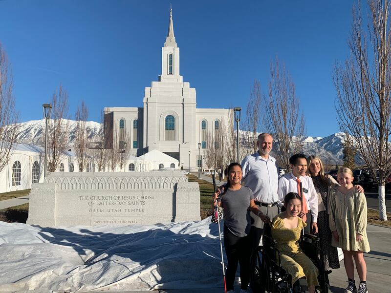 O Templo de Orem Utah realiza um passeio tátil para pessoas com deficiência visual em 5 de dezembro de 2023. Entre os convidados estão Lexi Green, de camisa cinza, Jeremy Green, de camisa de botão, élder Conner Green, de gravata vermelha, e Sophia Green, com vestido amarelo (na cadeira de rodas).