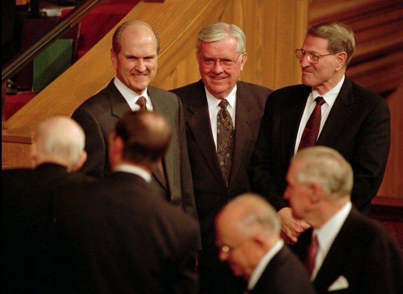 O então Élder Russell M. Nelson, Élder M. Russell Ballard e Élder Neal A. Maxwell, todos do Quórum dos Doze Apóstolos, assistem com rostos sorridentes à saída do Presidente Howard W. Hunter no final da conferência.