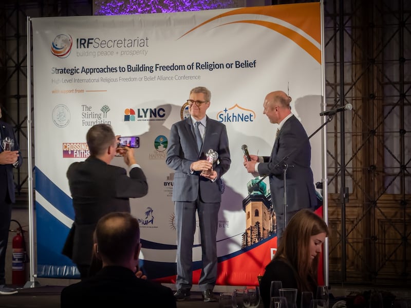 Professor Brett Scharffs do Centro Internacional para Estudos de Direito e Religião na Universidade Brigham Young recebe um prêmio por seu compromisso de longa data com a defesa da liberdade religiosa do Embaixador Robert Řehák, Presidente da Article 18 Alliance, durante uma cerimônia de premiação no histórico Museu Nacional em Praga, República Tcheca, em 12 de novembro de 2025.