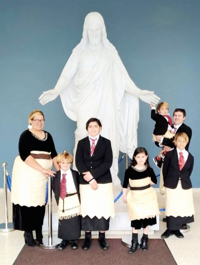 Os Stroms estão retratados em frente a uma estátua de Christus em trajes tradicionais tonganeses no início de agosto de 2022 no Templo de Hamilton Nova Zelândia.